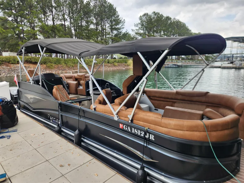 Slide: The Image of 2021 Premier 290 Grand View pontoon boat docked by a scenic lake. - 1