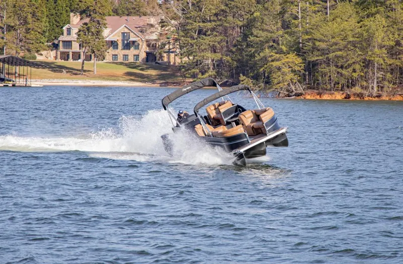 Slide: The Image of 2023 Premier 290 Grand View pontoon boat cruising on a scenic lake. - 2