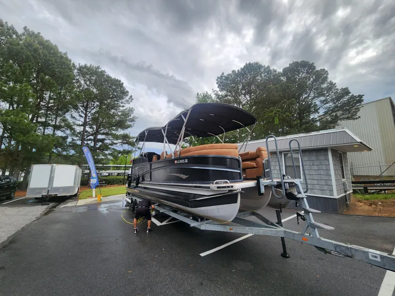 Slide: The Image of 2021 Premier 290 Grand View pontoon boat on trailer, parked outdoors under cloudy sky. - 20