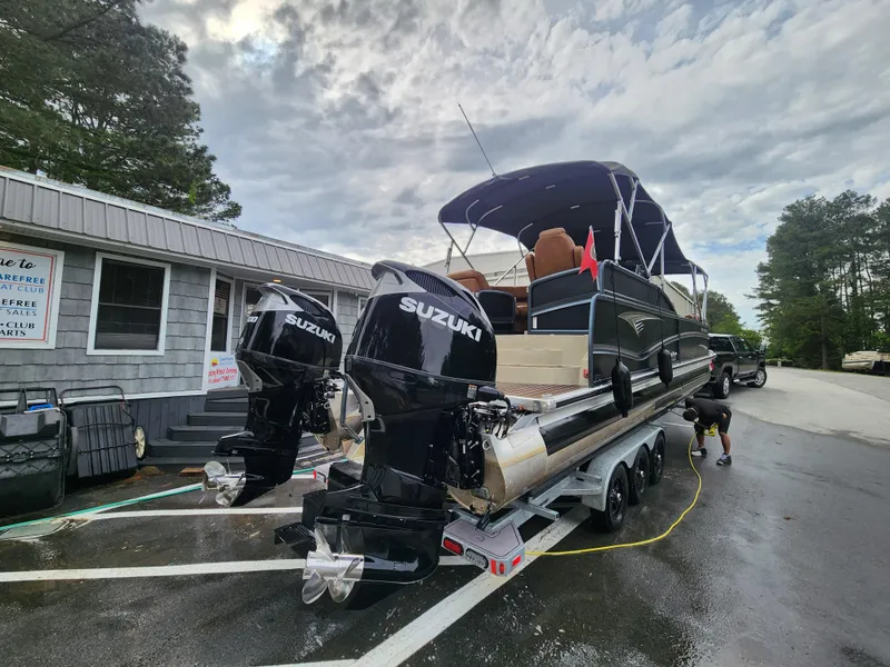 Slide: The Image of 2021 Premier 290 Grand View pontoon boat with dual Suzuki engines on a trailer. - 21