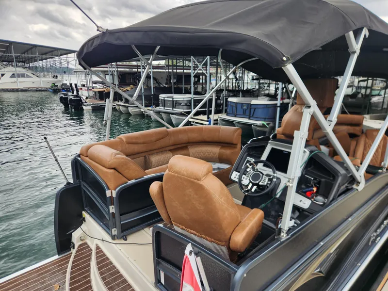 Slide: The Image of 2021 Premier 290 Grand View pontoon boat with tan seating and black canopy at marina. - 7