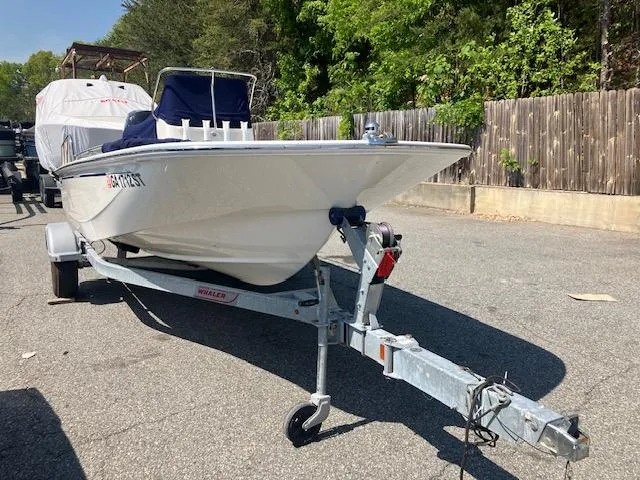 Slide: The Image of 2020 Boston Whaler 170 Montauk boat on trailer, parked outdoors near wooden fence. - 2