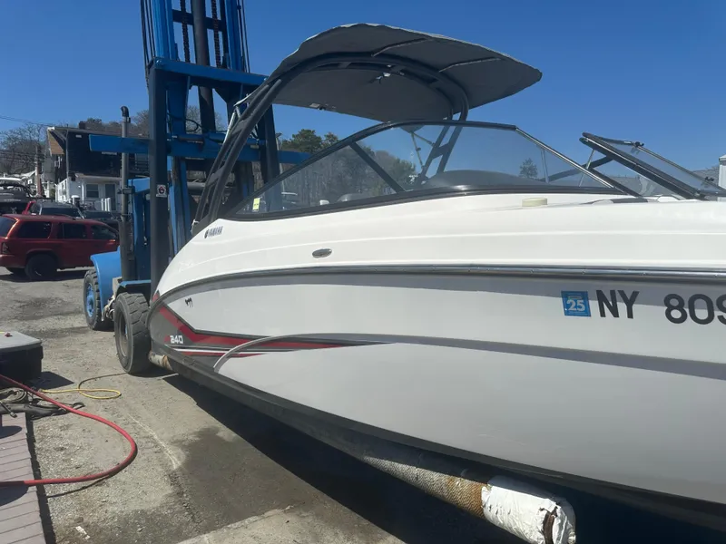 Slide: The Image of 2019 Yamaha AR240 boat on a lift, white with black and red accents, dockside. - 6