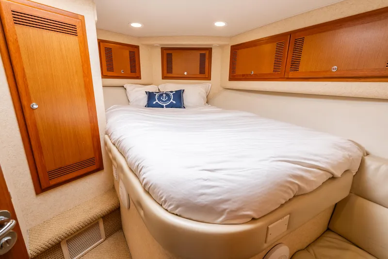 Slide: The Image of Luxurious cabin interior of 2004 Cabo 48 Flybridge yacht with cozy bed and wooden cabinets. - 11