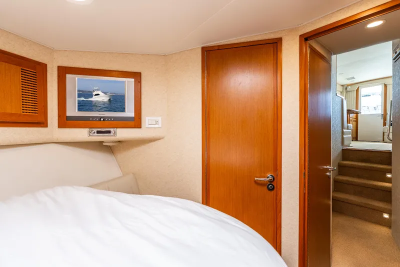 Slide: The Image of Interior of 2004 Cabo 48 Flybridge yacht bedroom with wooden doors and cozy bedding. - 12