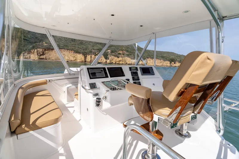 Slide: The Image of 2004 Cabo 48 Flybridge interior with helm, beige seating, and ocean view. - 24