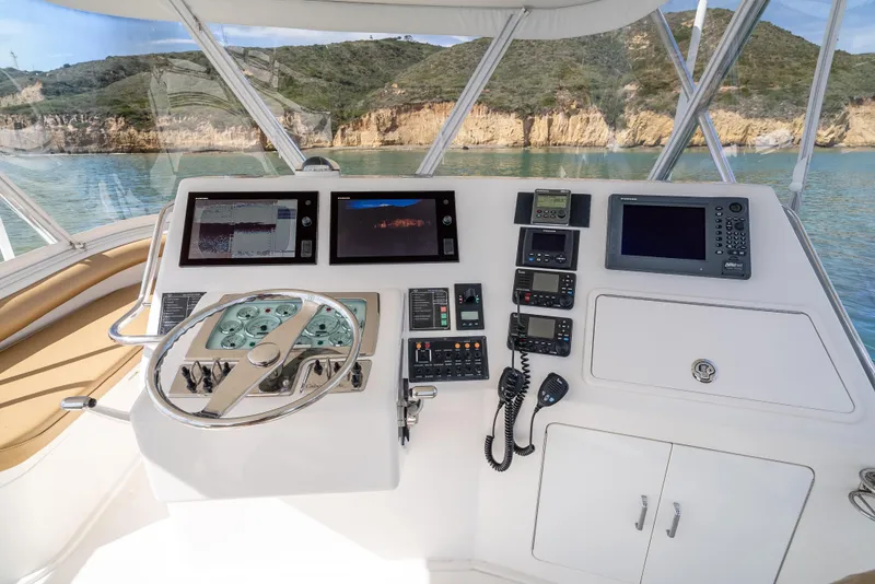 Slide: The Image of 2004 Cabo 48 Flybridge helm with modern navigation equipment and scenic coastal view. - 25