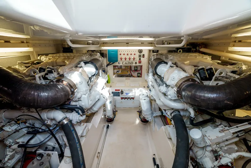 Slide: The Image of Engine room of 2004 Cabo 48 Flybridge yacht, featuring dual engines and control panel. - 28
