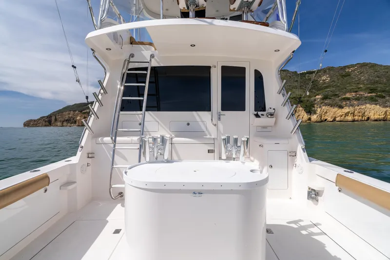 Slide: The Image of 2004 Cabo 48 Flybridge yacht with spacious deck and scenic ocean backdrop. - 34