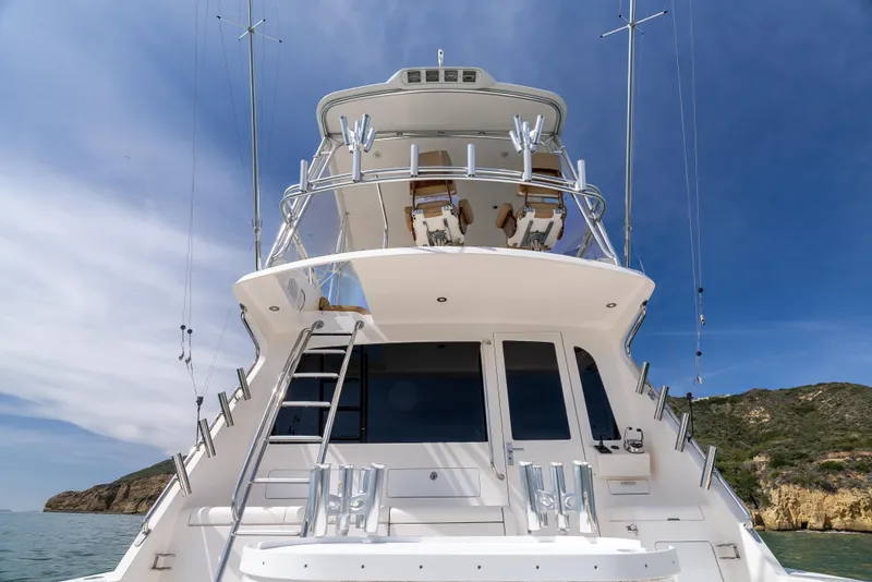 Slide: The Image of 2004 Cabo 48 Flybridge yacht with sleek design, docked near rocky coastline under blue sky. - 35