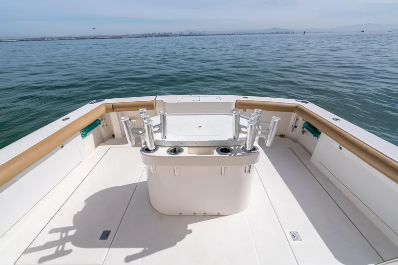 Slide: The Image of 2004 Cabo 48 Flybridge boat deck with rod holders, overlooking calm ocean waters. - 38