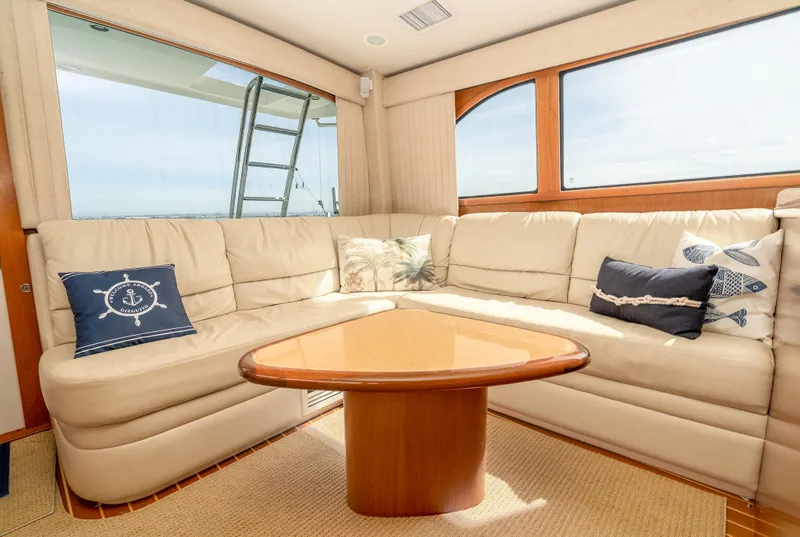 Slide: The Image of Luxurious interior of 2004 Cabo 48 Flybridge yacht with beige leather seating and wooden table. - 4