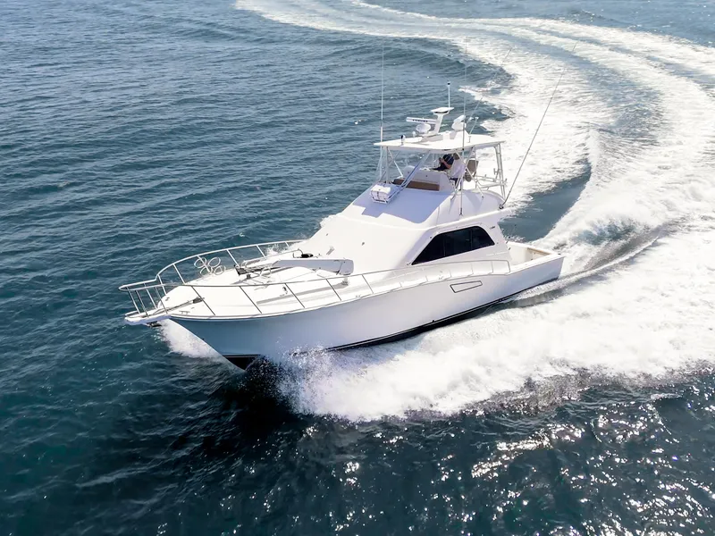 Slide: The Image of 2004 Cabo 48 Flybridge yacht cruising on open water, creating a dynamic wake. - 40