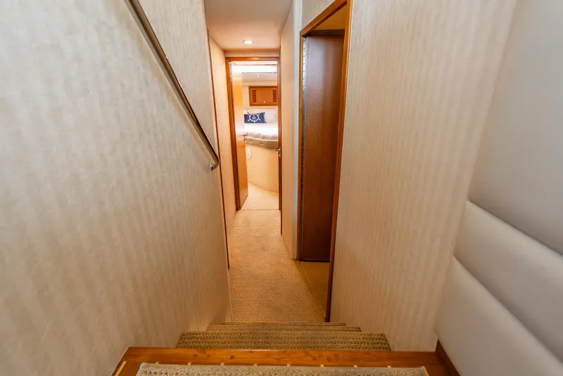 Slide: The Image of Interior hallway of 2004 Cabo 48 Flybridge yacht, featuring carpeted stairs and wooden accents. - 9