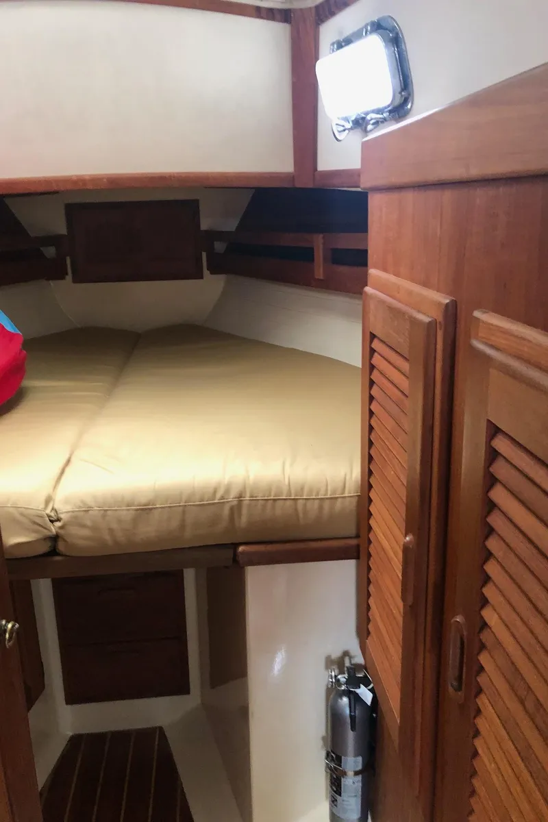 Slide: The Image of 1992 Pacific Seacraft 34 Crealock cabin interior with wooden cabinetry and cozy sleeping area. - 11