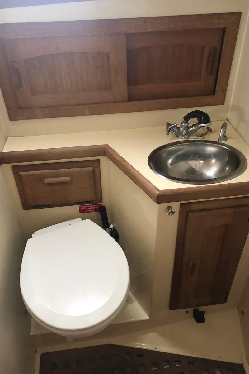 Slide: The Image of 1992 Pacific Seacraft 34 Crealock yacht bathroom with sink, toilet, and wooden cabinetry. - 12