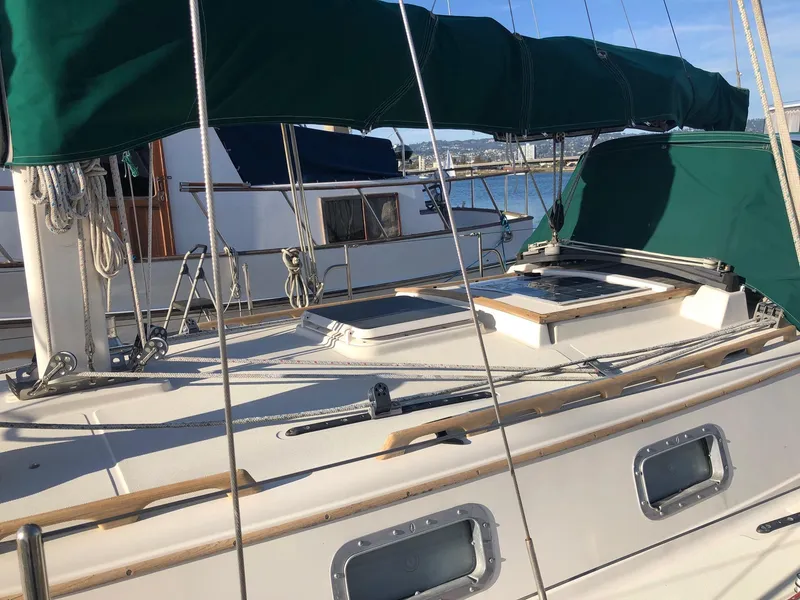 Slide: The Image of 1992 Pacific Seacraft 34 Crealock sailboat with green covers, docked at a marina. - 15