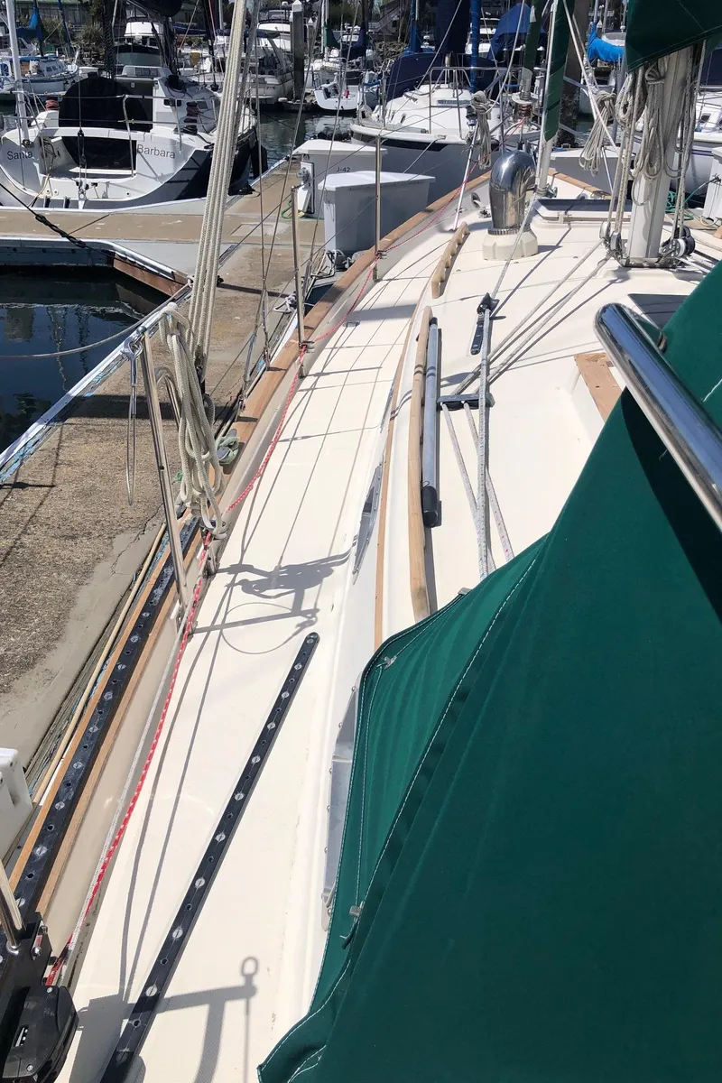 Slide: The Image of 1992 Pacific Seacraft 34 Crealock sailboat deck with green covers in marina. - 18