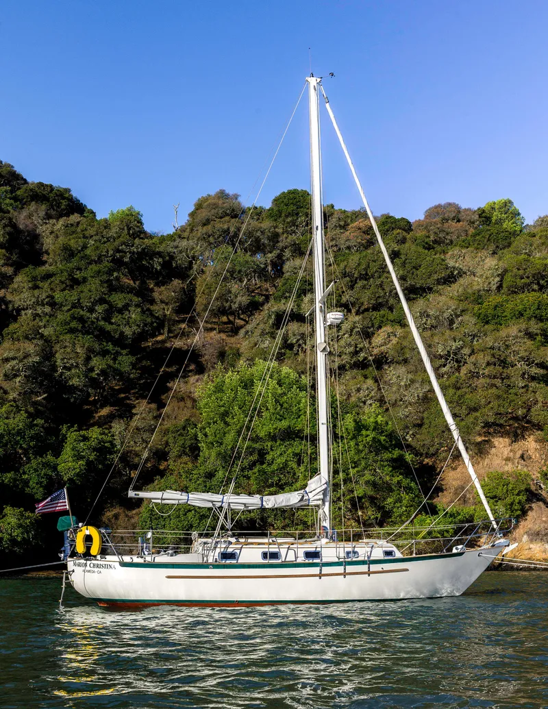 Slide: The Image of Sailboat Pacific Seacraft 34 Crealock 1992 anchored near lush green shoreline. - 22