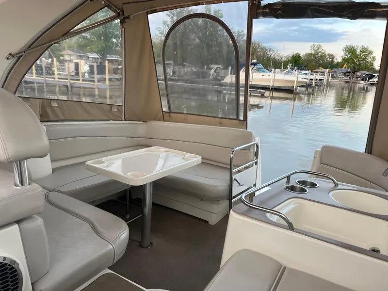 Slide: The Image of 2007 Larson Cabrio 330 boat interior with seating and table, docked by a calm marina. - 20