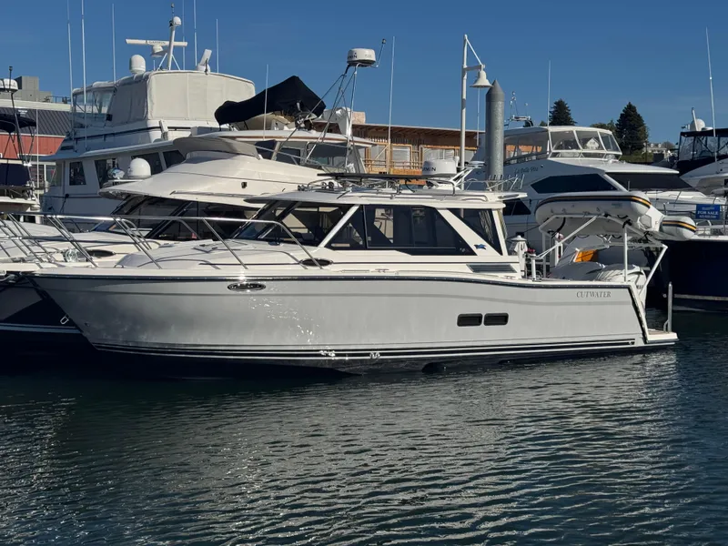 Slide: The Image of 2025 Cutwater C-288 Coupe yacht docked in a marina, surrounded by other boats. - 0