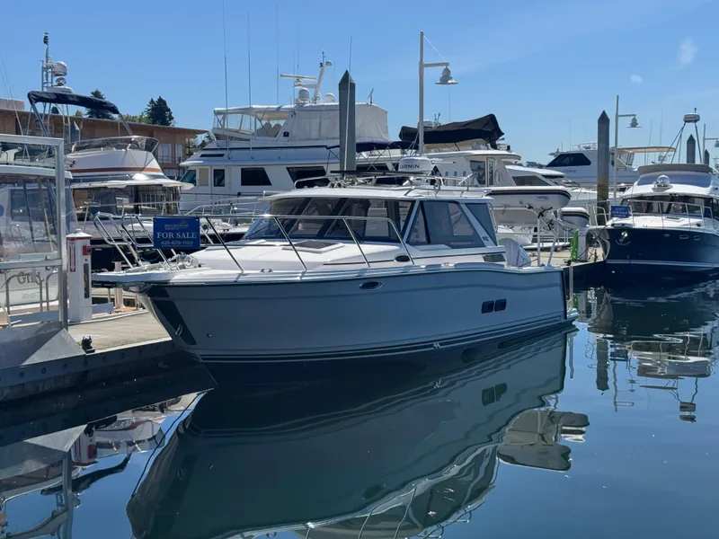 Slide: The Image of 2025 Cutwater C-288 Coupe boat docked in a marina, surrounded by other vessels. - 1