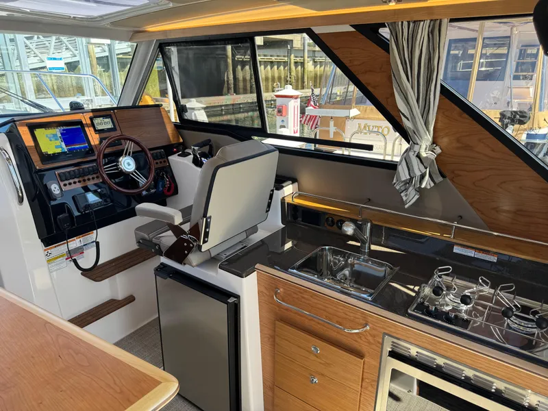 Slide: The Image of Interior of 2025 Cutwater C-288 Coupe featuring helm, kitchenette, and modern amenities. - 19