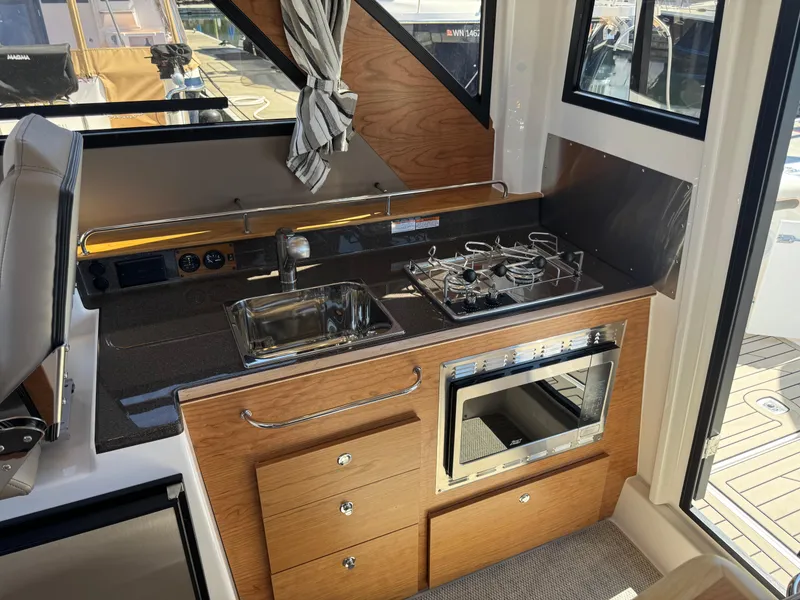 Slide: The Image of 2025 Cutwater C-288 Coupe interior kitchen with sink, stove, and microwave. - 21