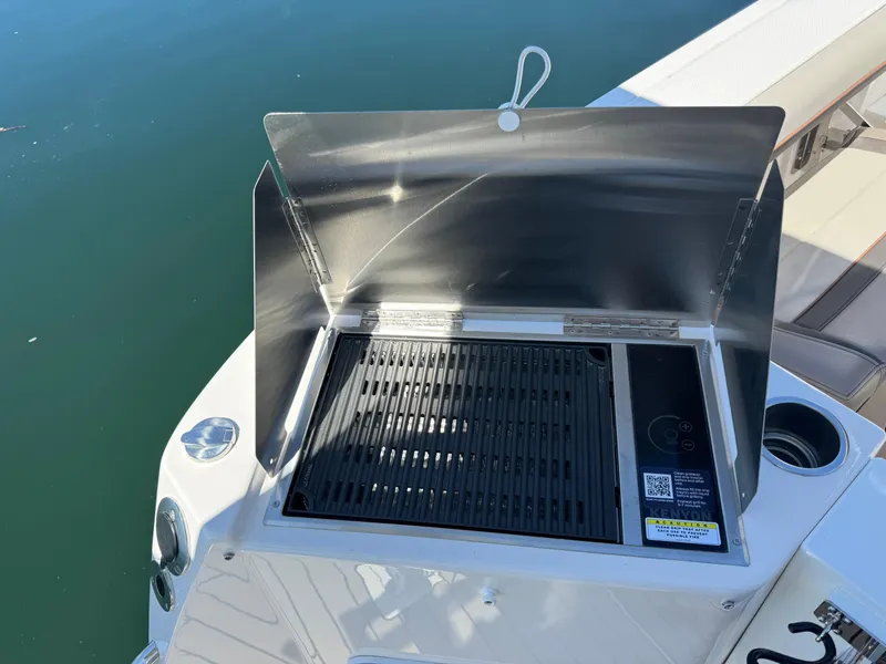 Slide: The Image of Outdoor grill on 2025 Cutwater C-288 Coupe boat, set against a serene water backdrop. - 6