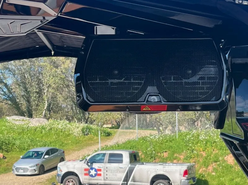 Slide: The Image of Outdoor speaker system on a 2025 Centurion Ri 265 boat, with trucks in the background. - 16