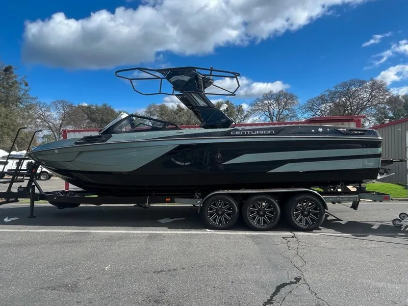Slide: The Image of 2025 Centurion Ri 265 boat on trailer, parked outdoors under a blue sky. - 5