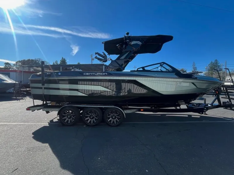 Slide: The Image of 2025 Centurion Ri 265 boat on trailer under clear blue sky. - 7