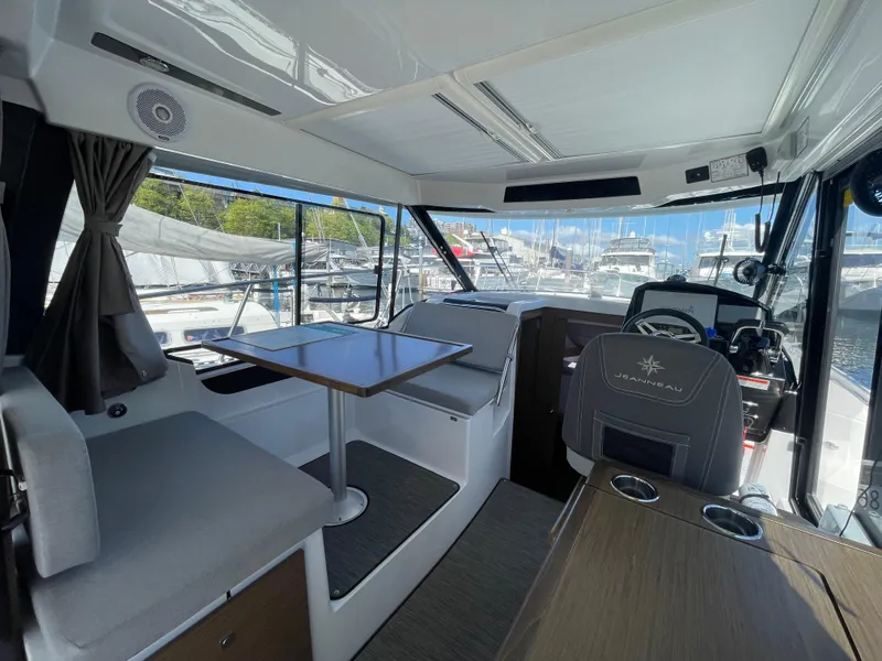 Slide: The Image of 2019 Jeanneau NC895 interior with seating, table, and helm, docked at marina. - 11
