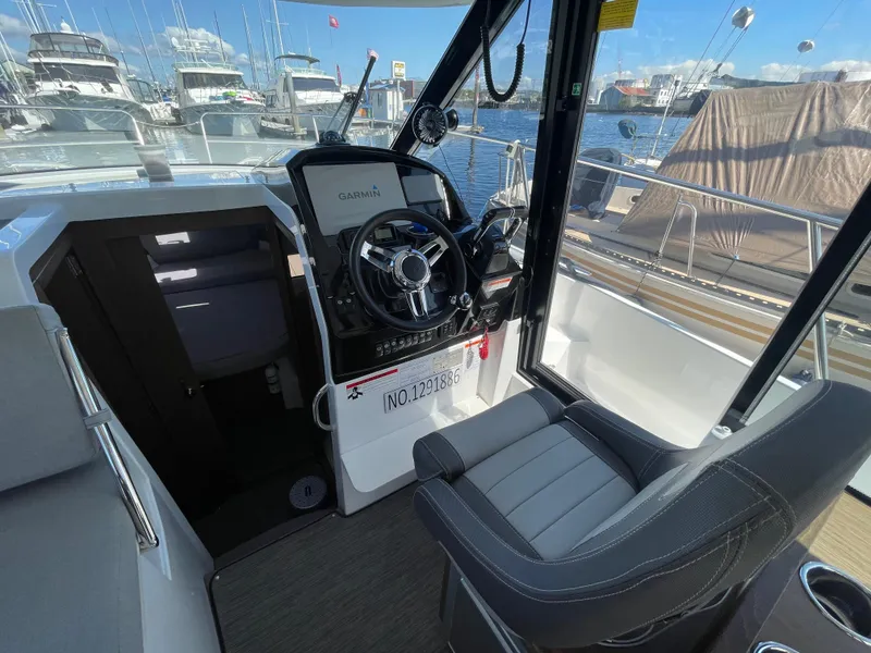 Slide: The Image of 2019 Jeanneau NC895 helm with steering wheel, Garmin display, and marina view. - 17