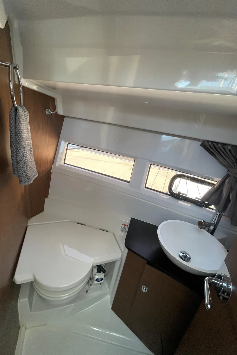 Slide: The Image of 2019 Jeanneau NC895 boat bathroom with compact toilet, sink, and window. - 30