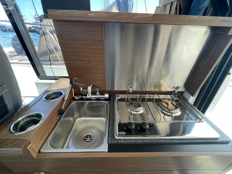 Slide: The Image of 2019 Jeanneau NC895 boat kitchen with sink and dual-burner stove. - 9