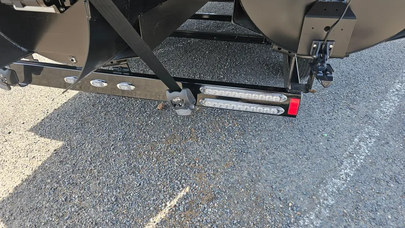Slide: The Image of 2025 Manitou 24' Explore MAX Deck Navigator trailer hitch detail on asphalt. - 22