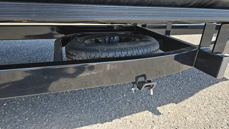 Slide: The Image of 2025 Manitou 24' Explore MAX trailer with spare tire underneath on asphalt. - 31