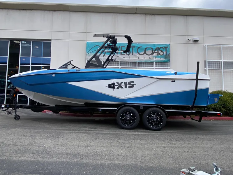 Slide: The Image of 2025 Axis T250 boat in blue and white on a trailer outside a building. - 1
