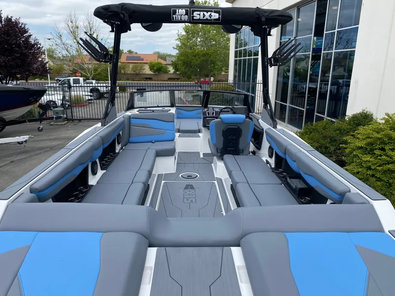 Slide: The Image of 2025 Axis T250 boat interior with blue and gray seating, docked near a building. - 12