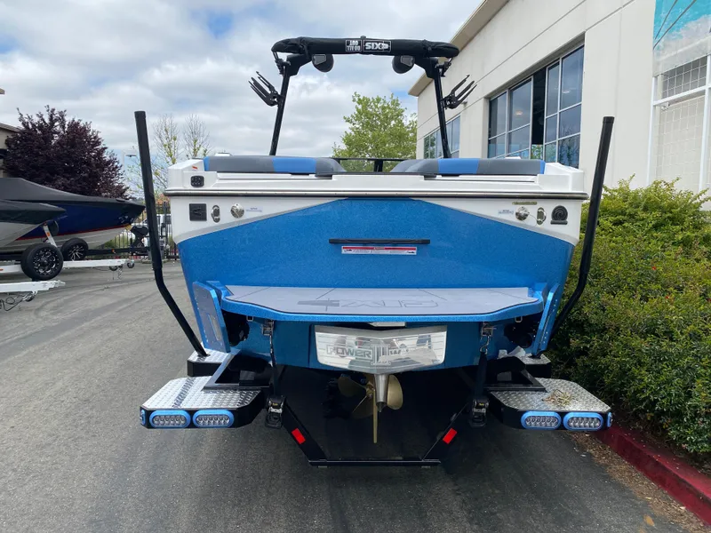 Slide: The Image of 2025 Axis T250 boat, blue exterior, rear view, parked outdoors near a building. - 3