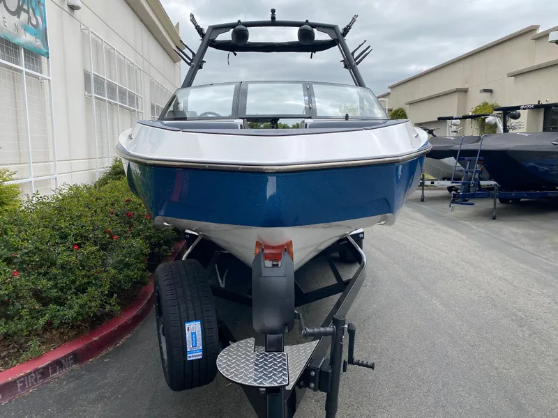 Slide: The Image of 2025 Axis T250 boat on trailer, blue and white exterior, parked outdoors. - 4