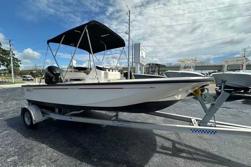 Slide: The Image of 2022 Boston Whaler 170 Montauk boat on trailer, parked outdoors under a cloudy sky. - 7