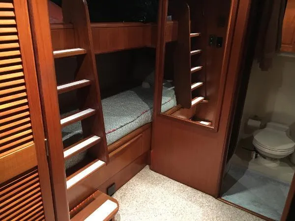 Slide: The Image of 1990 Viking Extended Aft Deck Motor Yacht interior with wooden bunk beds and bathroom. - 16