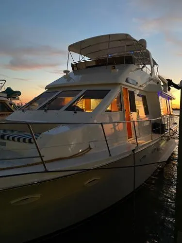 Slide: The Image of 1990 Viking Extended Aft Deck Motor Yacht at sunset, docked with illuminated interior. - 4