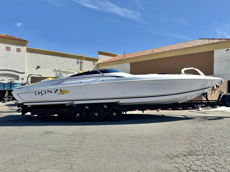 The Image of 2004 Donzi 38 ZX powerboat on trailer, parked outdoors under clear blue sky. - 0