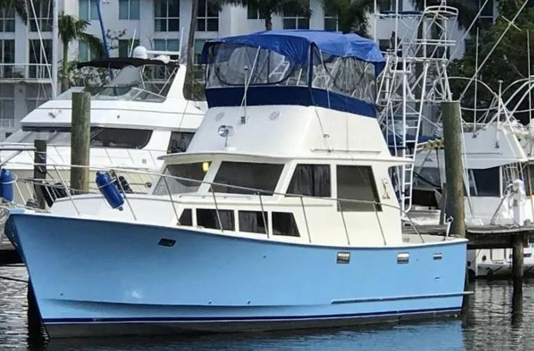 Slide: The Image of 1985 Roughwater 36 boat docked in marina, featuring blue and white exterior. - 1