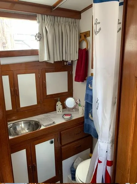 Slide: The Image of 1985 Roughwater 36 boat bathroom with wooden cabinets, nautical decor, and stainless steel sink. - 13