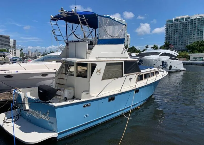 Slide: The Image of 1985 Roughwater 36 boat docked in marina, blue and white exterior, clear sky background. - 2