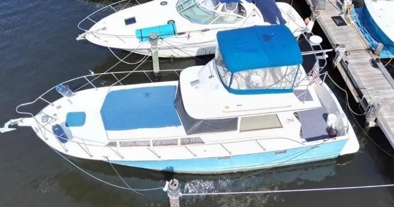 Slide: The Image of 1985 Roughwater 36 boat docked, aerial view, blue canopy, white deck, marina setting. - 3